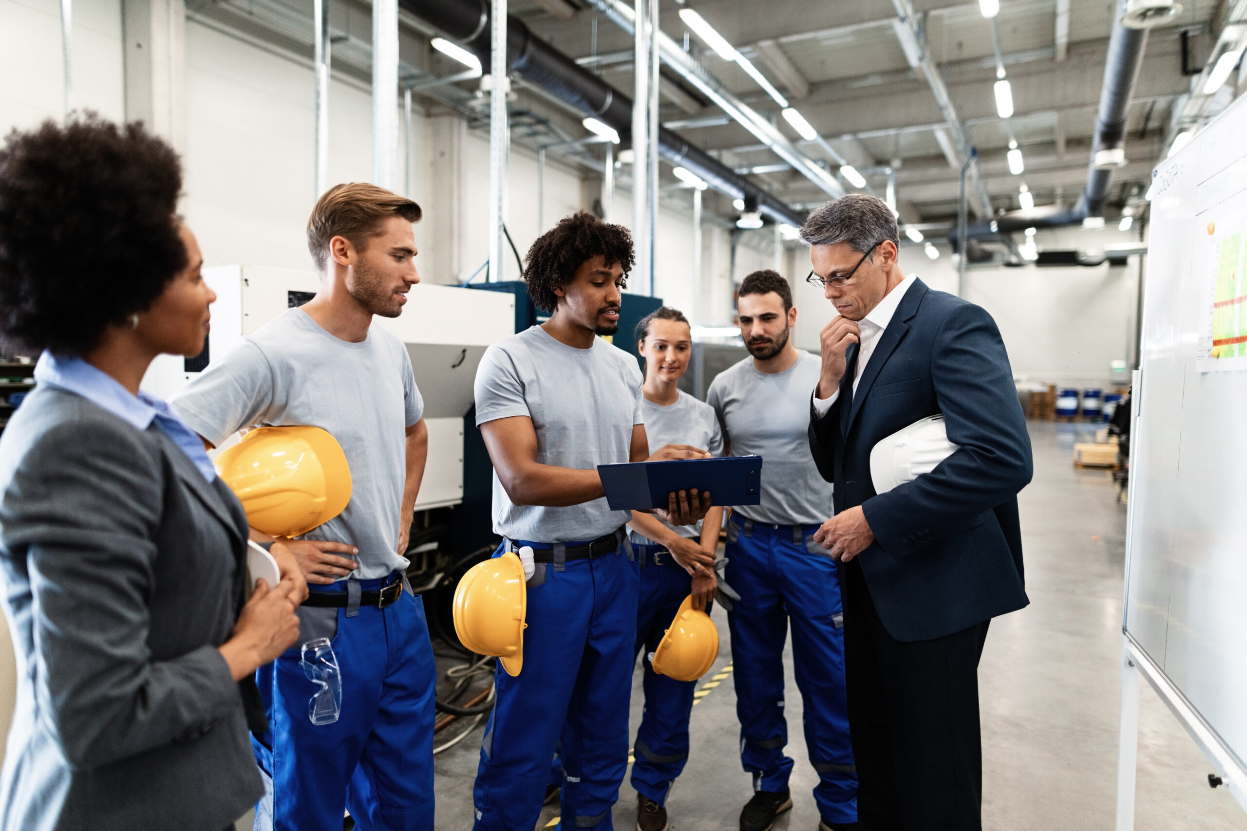 Company manager and African American worker cooperating while analzying production plans on a meeting in a factory.